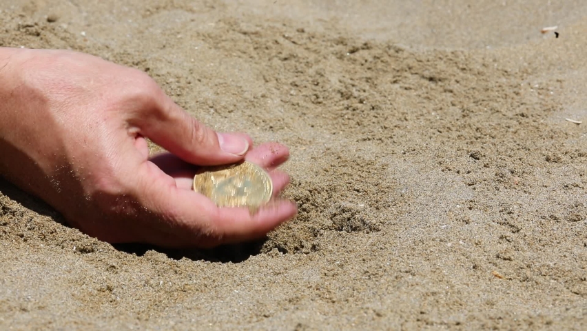 Hand of the person digging in the sand to find golden bitcoin coins | Shutterstock HD Video #1093000559