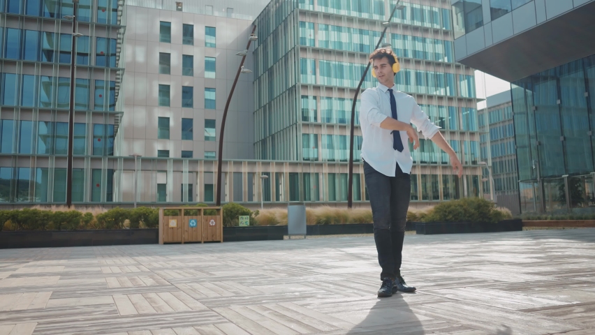  Flexible and cool businessman doing acrobatic tricks outdoor. Young business man having fun dancing while going to work.