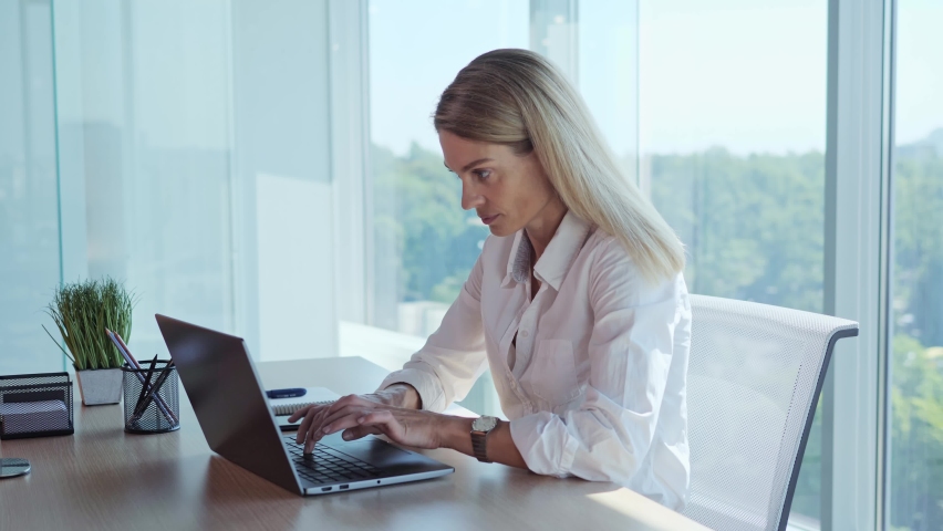 Happy businesswoman finish working on laptop, put hands behind head lean on comfy office chair for productive workday near panoramic window, good posture. Fruitful work accomplishment concept. Royalty-Free Stock Footage #1093003667