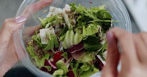 A woman mixing salad in a plastic bowl. Close up footage of a woman mixing salad in a plastic bowl. Beautiful footage of a woman mixing salad in a plastic bowl