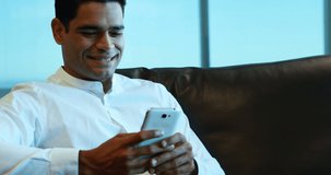 Animation of person icon and speech bubble over smiling asian man using smartphone. Global communication network, business and social media concept digitally generated video.