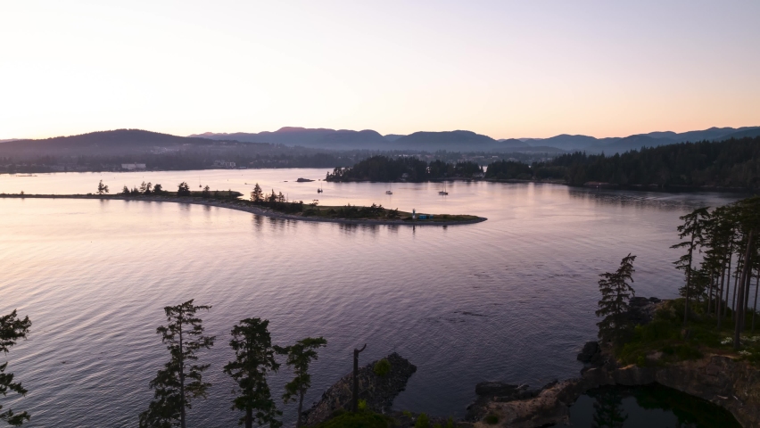 Aerial hyperlapse of ocean sunset, peninsula, boats in harbour, peaceful ocean sunset, Whiffen Spit, Sooke, Vancouver Island. 4K 24FPS