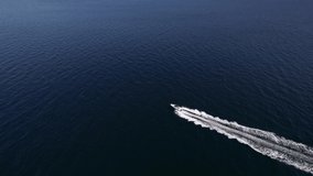 Aerial footage of a speed boat racing across the ocean, waves, boat wake, sunny day summer, happy life, luxury life. 5.4K to 4K 24FPS.