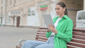 Online Video Chat on Tablet by Hispanic Woman Sitting Outdoor on Bench 