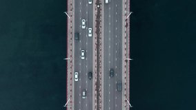 4k Top view of cars driving on road surrounded by waters in countryside irrl. Above pic of lot of transport rides along highway among blue waters of lake or river away from city on summer day. Video