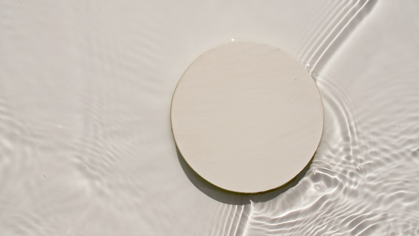 Empty white circle podium on transparent clear water texture with waves in sunlight. Background for product presentation. Flat lay cosmetic mockup, copy space.