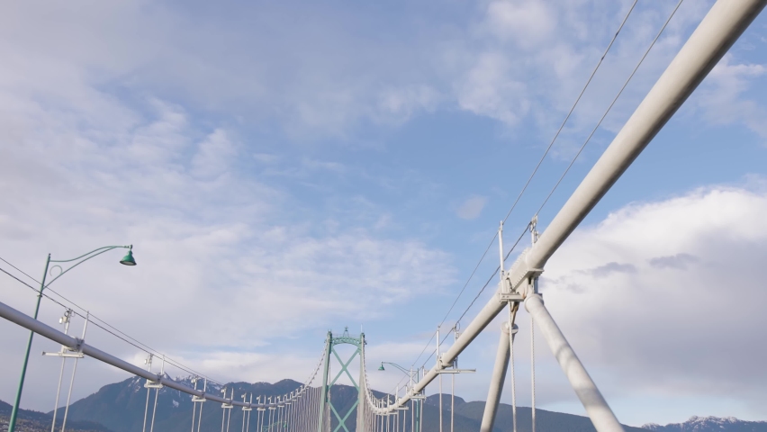 Driving Across Lions Gate Bridge with Mountains and Blue Sky in Background. Downtown Vancouver, British Columbia, Canada.