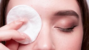 A young beautiful girl removes makeup with a cotton pad and micellar water from her face and eyes. - Powered by Shutterstock - Get 15% off with code: PIKWIZARD15