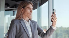 Business woman having video call on smartphone in slow motion. Close up serious businesswoman making video chat online on mobile phone in office. Focused freelancer talking conference call. 