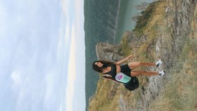 shot of a young woman with an athletic body carrying a bag and a mat in sportswear walking on a mountain path with a beautiful view for outdoor yoga or fitness.Vertical video