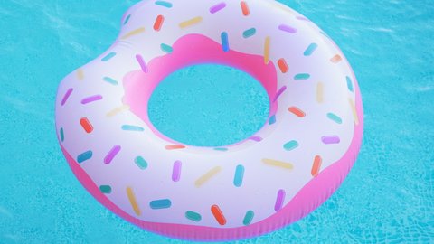 Pink inflatable donut ring floating in clear blue swimming pool. Top view. Summer colorful background. Vacation, relax. tropical concept.
