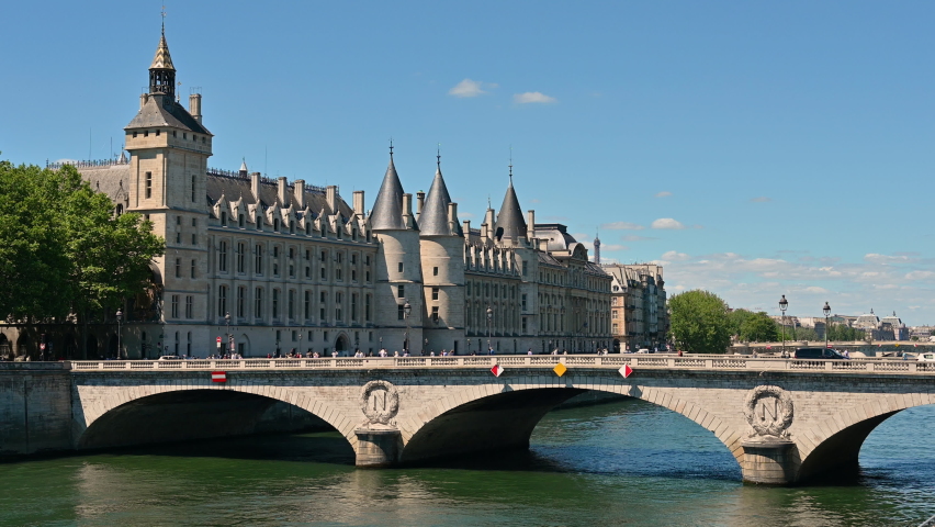 Nice footage of the Conciergerie Castle and Bridge of Change (Pont au Change) over the Seine. Passing of pedestrians and cars on the bridge, beautiful summer day.