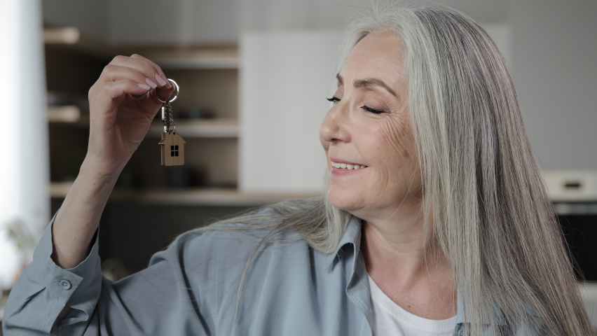 Gray-haired female buyer homeowner broker caucasian woman old granny seller holds bunch keys of rental apartment flat leases lodging room new dwelling win home accommodation modern housing