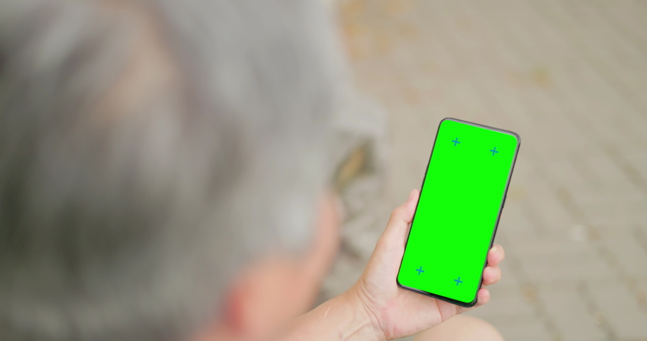 rear view of gray hair old senior asia man looking green screen phon in hand sitting on bench outdoor Royalty-Free Stock Footage #1093051031
