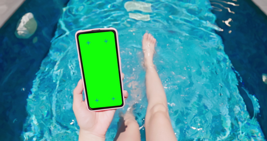 slow motion point of view asian girl is kicking feet underwater in rippled clear blue water and using green screen smartphone on swimming pool Royalty-Free Stock Footage #1093051145