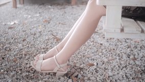 slow motion video The beautiful legs of a woman sitting on a swing in the garden