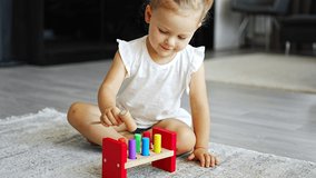 Cute caucasian little girl playing on the floor at home with eco wooden toys. Montessori toy. The child playing educational games. High quality 4k footage