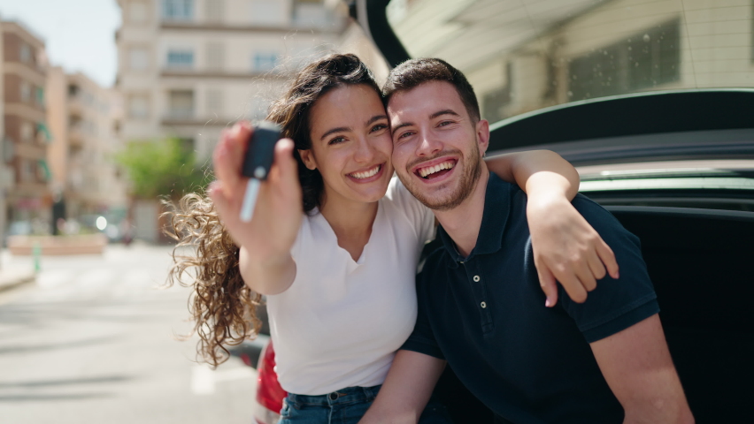 Young hispanic couple hugging each other holding key of new car at street | Shutterstock HD Video #1093061193