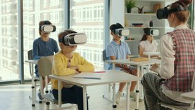 Multicultural school children using virtual reality headsets in classroom with teacher. Teacher is showing how to use virtual reality in the class. People technology and education concept - Powered by Shutterstock - Get 15% off with code: PIKWIZARD15