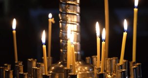 Burning candles in a gilded candlestick in the Orthodox church. The concept of Christianity, religion, faith, rituals, funeral services, Orthodoxy, churches and temples. 4K video 4096x2160
