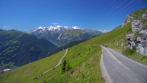 Scenic view of a green grassy hill, a mountain flower meadow and the snowy peaks of the Alps in Verbier, Switzerland. Place for photo Panorama . Cyclists. parachuting. Verbier Swiss 07.2022