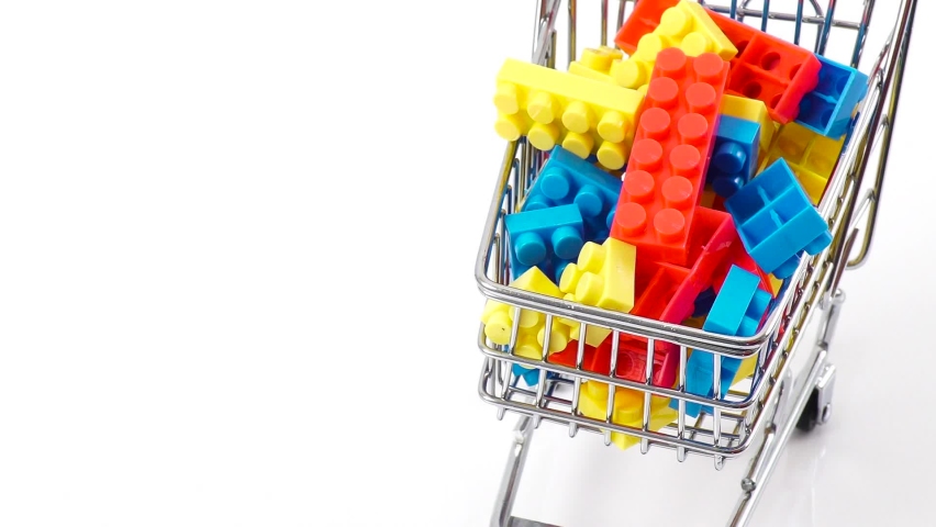 Hand pushing miniature toy supermarket trolley. The trolley has multi-colored toy plastic building blocks, bricks. Herbal complex. White background. Place for text. Shopping concept. | Shutterstock HD Video #1093074689