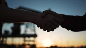 handshake oil contract. handshake a worker and businessman shaking hands against the backdrop of an oil pump. oil extraction business concept. silhouette close-up handshake business contract - Powered by Shutterstock - Get 15% off with code: PIKWIZARD15