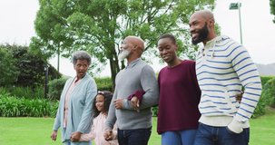 Video of happy african american parents and grandparents walking with granddaughter in garden. Family, domestic life and togetherness concept digitally generated video.