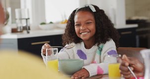 Video of happy african american daughter laughing and eating with family at dinner table. Family, domestic life and togetherness concept digitally generated video.