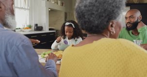 Video of happy african american grandmother turning and smiling at family breakfast table. Family, domestic life and togetherness concept digitally generated video.
