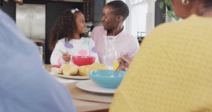 Video of happy african american daughter laughing and feeding mother at family breakfast table. Family, domestic life and togetherness concept digitally generated video.