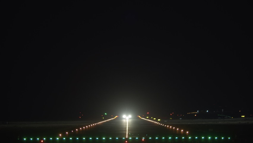 Frontal - the plane takes off into the night sky, picking up speed on a brightly lit runway Royalty-Free Stock Footage #1093088157