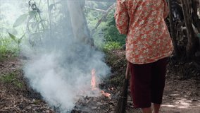 slow motion video Grandma was cleaning by burning dry leaves, causing smoke.