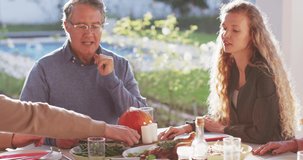 Video of happy caucasian parents, daughter and grandfather sitting at outdoor table for family meal. Family, domestic life and togetherness concept digitally generated video.