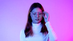 Metaverse concept, 4K video of young asian woman in white costume wearing vr goggles glasses posing watching touching playing on the purple screen background.