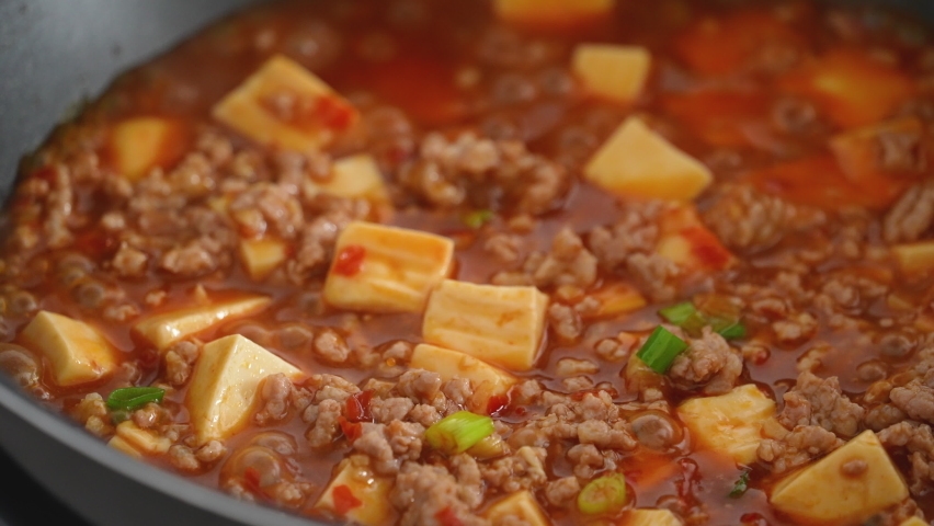 Cooking Mapo tofu. Homemade stir-frying tofu with hot spicy sauce in a pot at home.