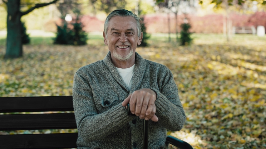 Portrait of senior man sitting on bench in park during the autumn. Shot with RED helium camera in 8K  