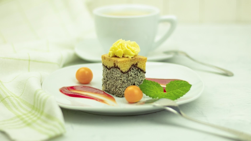 A delicious piece of sponge cake on a white plate. Sweet poppy cake with berries and mint on a plate. Physalis berries. Zooming in, zooming in on the camera | Shutterstock HD Video #1093096829