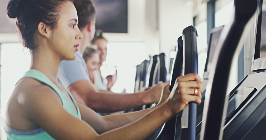 An active fitness woman exercising on a treadmill machine at a gym facility. Group of fit, serious and determined people running, jogging or training on modern equipment and keeping track of | Shutterstock HD Video #1093098121