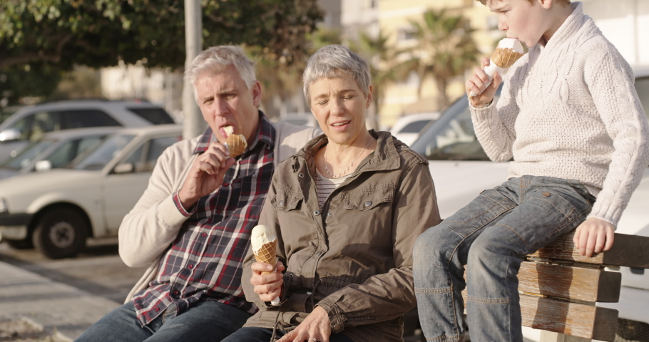 Smiling, happy and loving grandparents and grandson eating ice cream on a fun day. Mature couple and child smiling and talking together. Cute family group enjoying the sunshine and relaxing outdoors | Shutterstock HD Video #1093098153