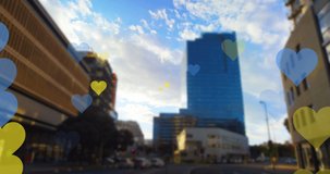 Animation of yellow and blue hearts floating over cityscape. ukraine crisis and international politics concept digitally generated video.