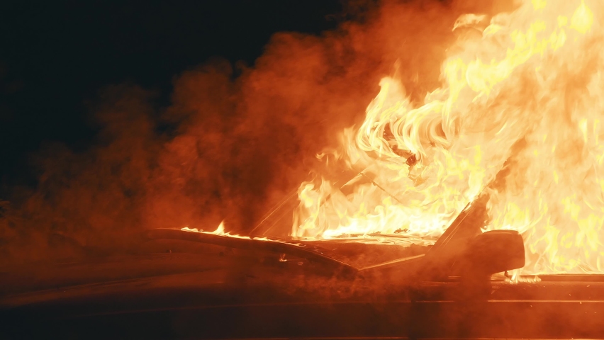 The interior of an old car destroyed in fire. Hood of the automobile covered with smoke, catching fire due to the accident at night time