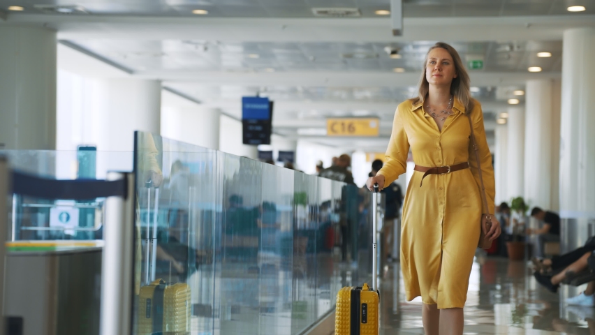 Woman with suitcase walking in airport terminal.