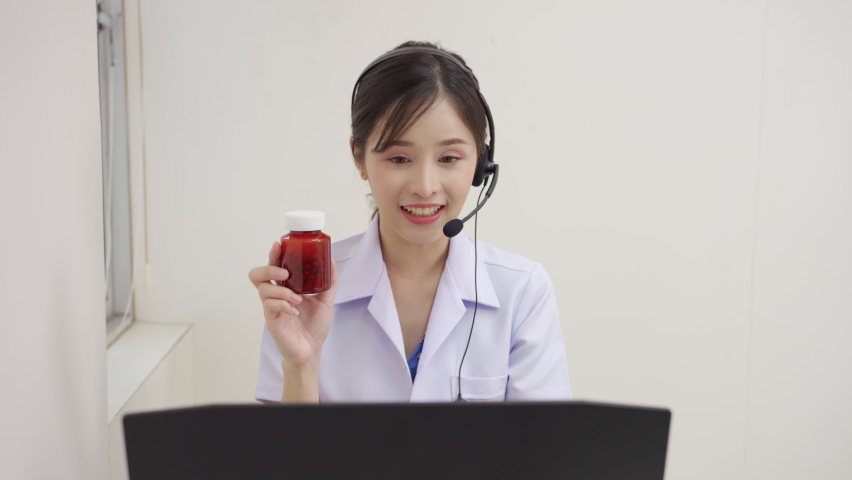 Asian Female doctor wears a headset and uses a laptop to do the talking and give medication instructions to their patient remotely via telemedicine at the hospital. Telemedicine online, communication | Shutterstock HD Video #1093106653