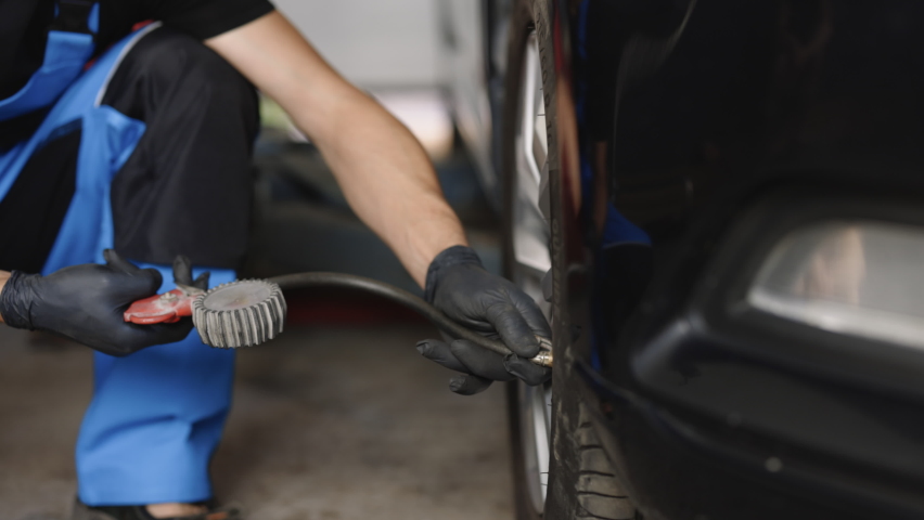 Mechanic inflating a car tire. Gas pumping of a car wheel. Car tire inflation. Car tire pressure check using air pressure guage. Royalty-Free Stock Footage #1093107971