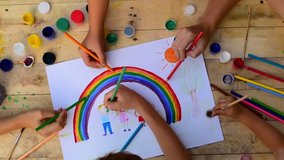 Group of children drawing with colored pencils and paints on wooden floor. Kids make painting family and bright rainbow. Top view. - Powered by Shutterstock - Get 15% off with code: PIKWIZARD15