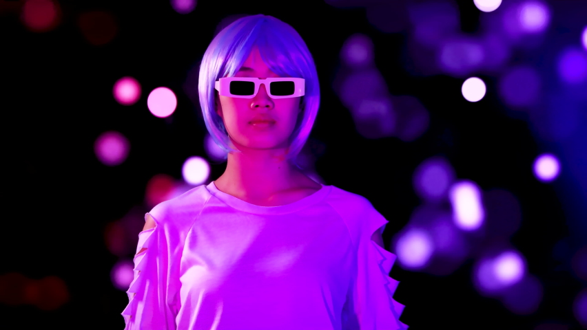 Young asian woman silver and blue hair style wearing vr glasses moving like robot on the blurred bokeh light and dark background. 4K video cyborg girl.  | Shutterstock HD Video #1093109137