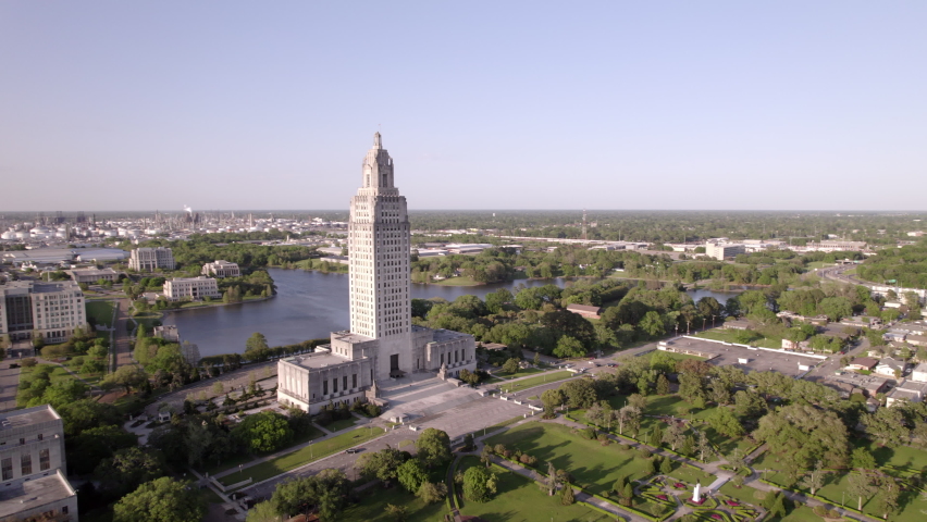 Aerial Panning Shot Of State Capitol Building Against Clear Sky In City, Drone Flying Over Green Landscape - Baton Rouge, Louisiana