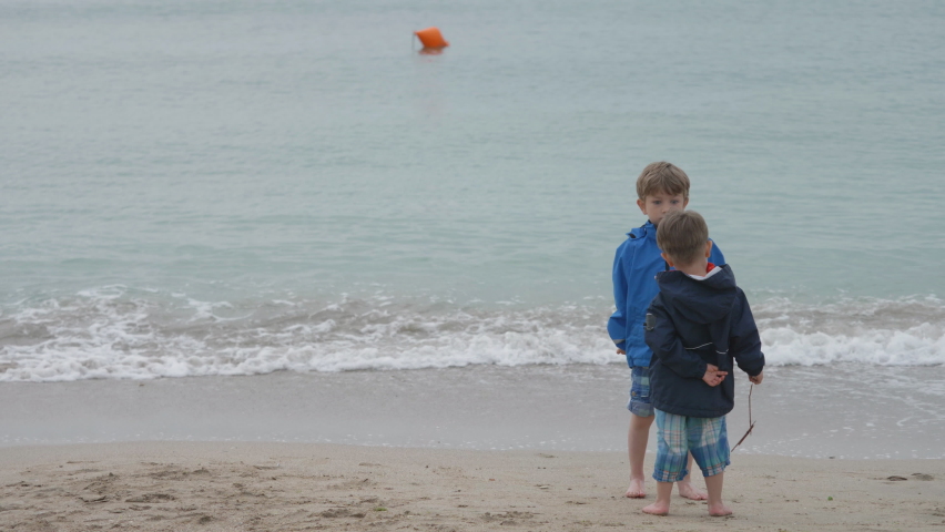 Little boys playing on the beach on cold weather