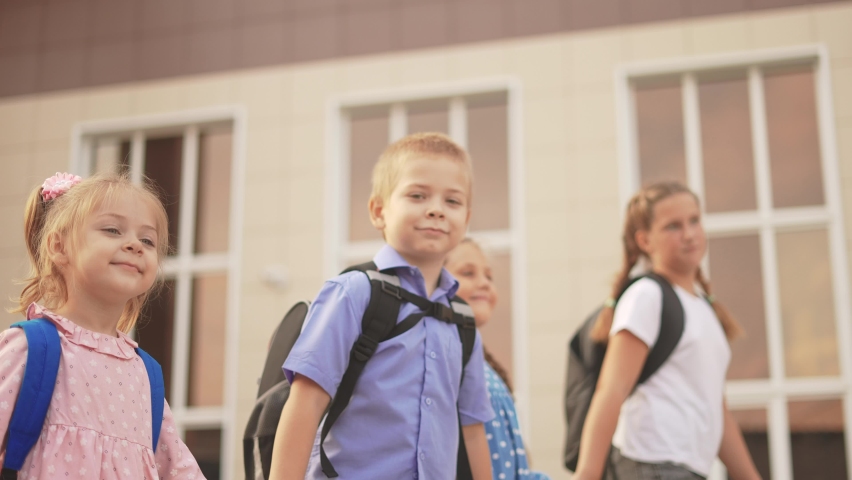 back to school. a group of schoolchildren with backpacks walk next to the school. lifestyle education kids concept. schoolboy and schoolgirl going to school. a group of children walking